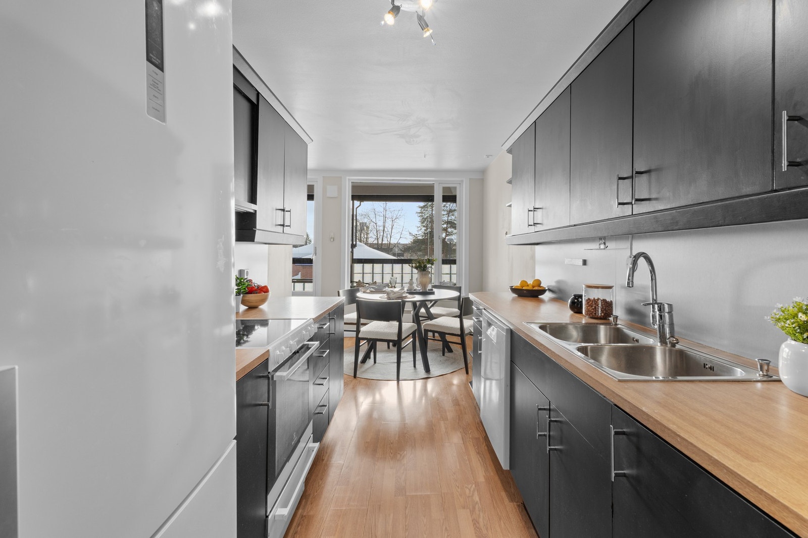 Delvis adskilt kjøkken med komfyr med platetopp, oppvaskmaskin og frittstående kjøl/fryseskap Galleribilde