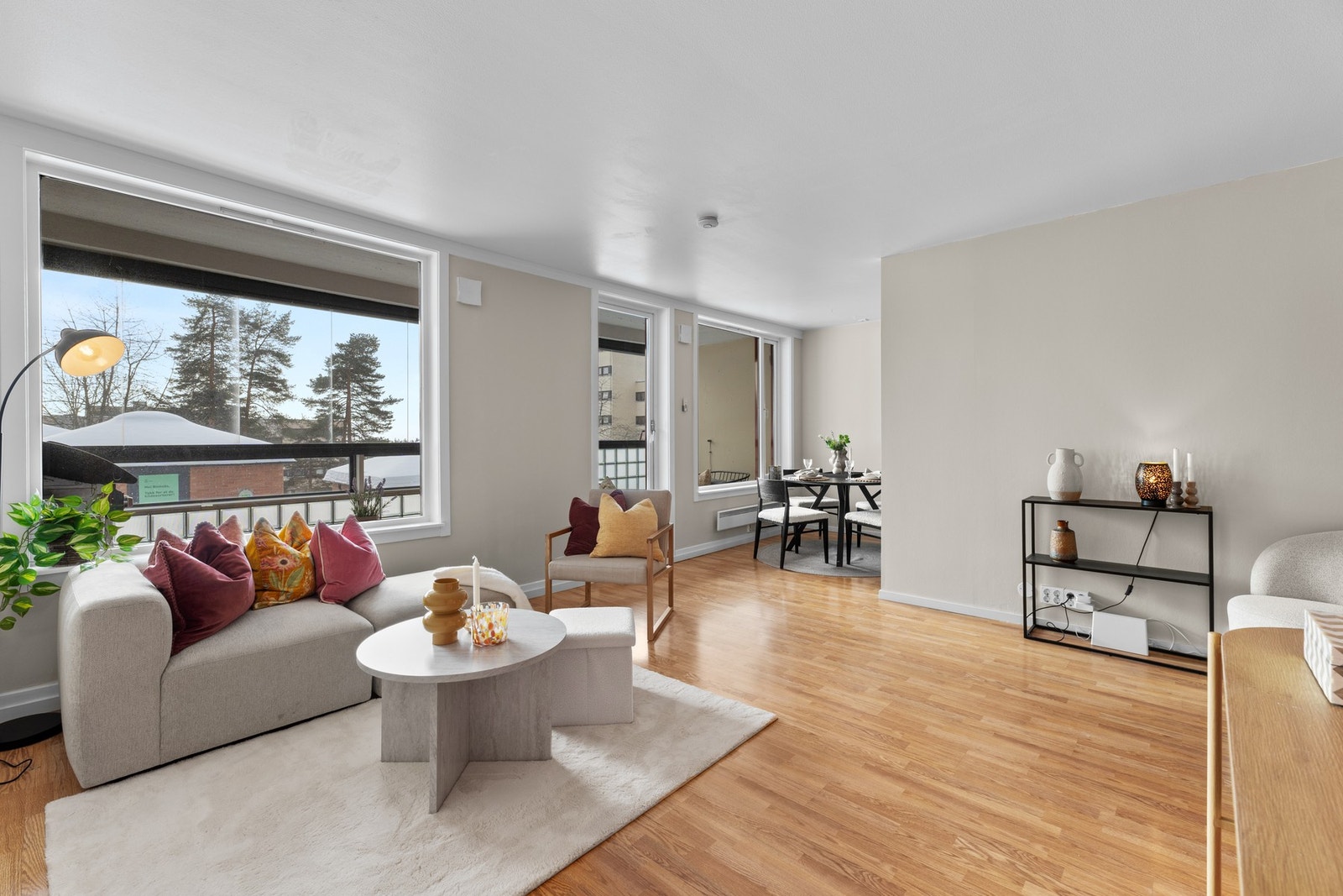 Romslig stue med plass til sofagruppe med tilhørende tv-bord ovenfor og spisegruppe ved kjøkkenet Galleribilde