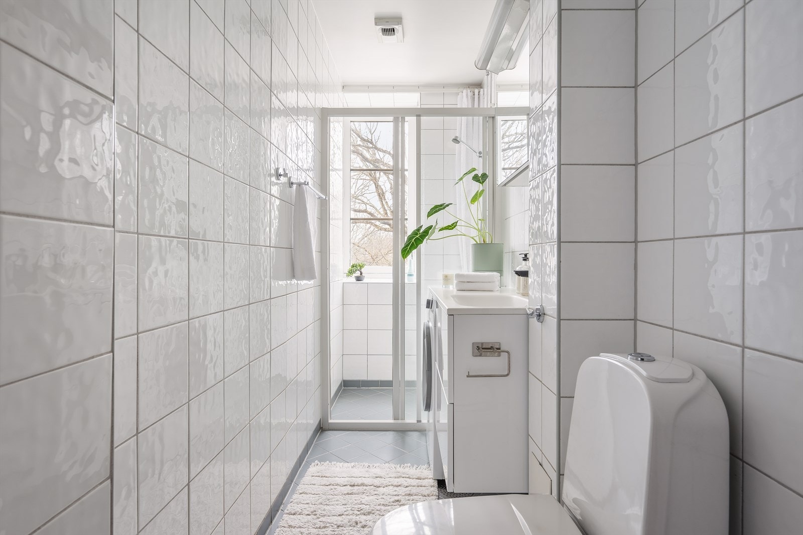 Badet byr på moderne servant med speilskap, toalett, praktisk oppbevaringsskap og dusjhjørne med glassskyvedør. Galleribilde