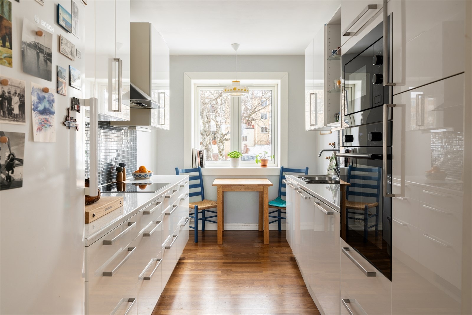 Kjøkkenet har en funksjonell utforming med glatte, hvite fronter og integrerte hvitevarer. Galleribilde