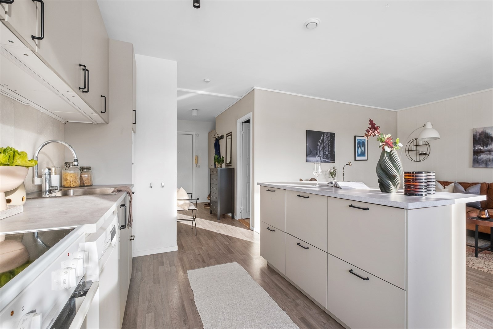 Innredningen med glatte fronter, benkeplate i laminat, opplegg for oppvaskmaskin, våtromsplater over kjøkkenbenk og waterguard i benkeskap. Galleribilde