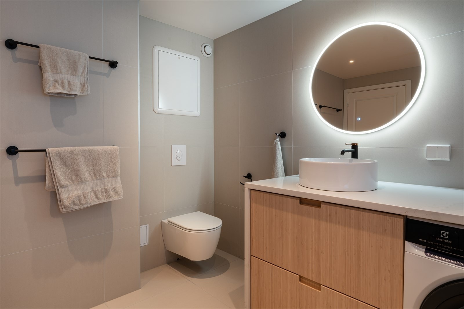 Speil med integrert belysning og et vegghengt toalett med skjult sisterne. Galleribilde