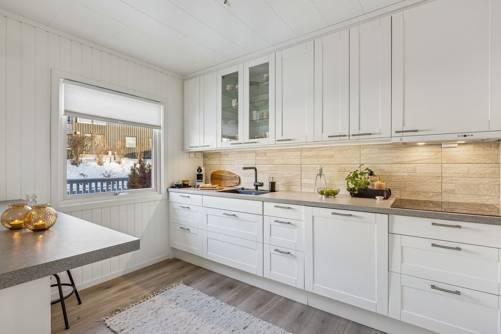 Hvitt, stilrent kjøkken med integrerte hvitevarer. Nisje for kjøleskap. Galleribilde