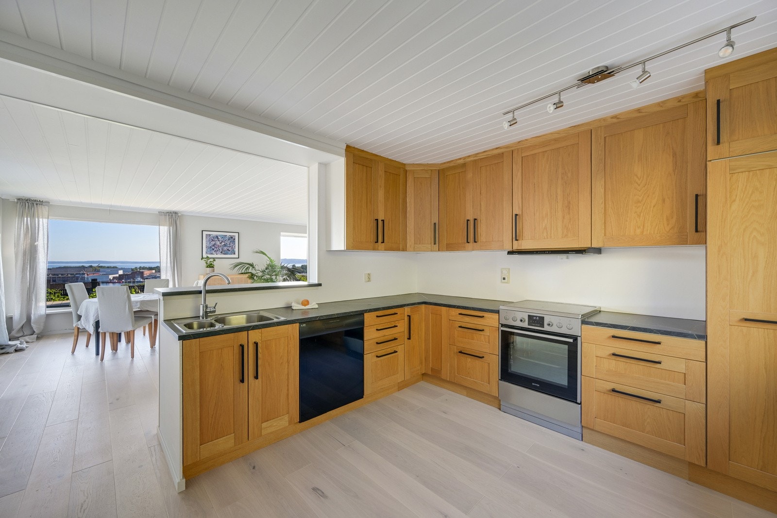 Pent og klassisk eike-kjøkken i åpen løsning til stua - fjordutsikt fra oppvaskkummen... Galleribilde