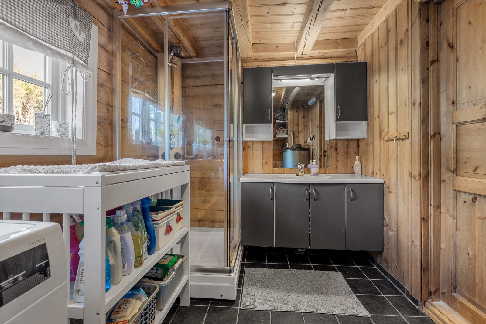 På badet er gulvet flislagt og med varmekabler, og veggene og taket er kledd med panel og tømmer, som gir rommet en varm og naturnær følelse. Galleribilde