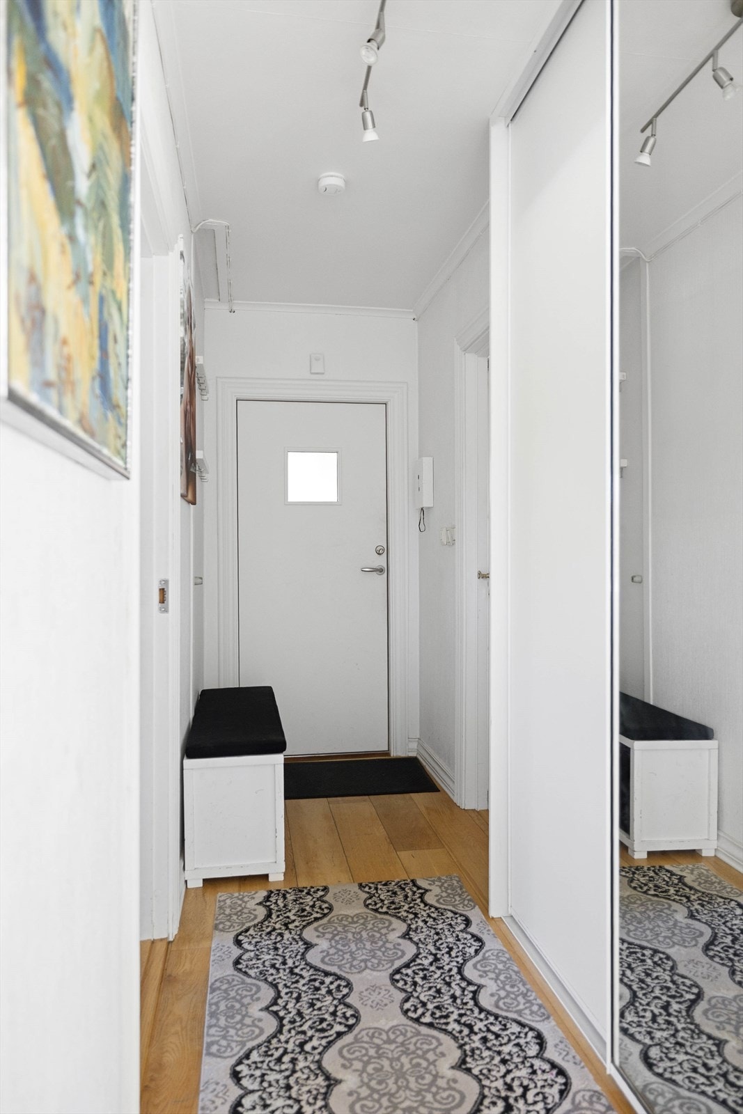 Det er inngang til leiligheten fra felles trapperom. Gangen inne har gode garderobeløsninger med blant annet skyvedørsgarderobe med speilfronter Galleribilde