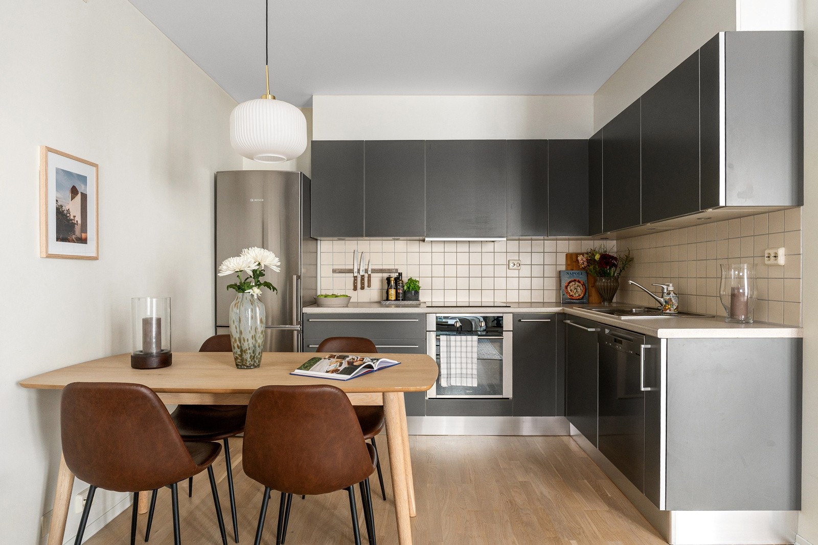 Pent kjøkken fra Aster innredet med slette fronter, stålhåndtak og overskap med praktisk benkebelysning. Galleribilde