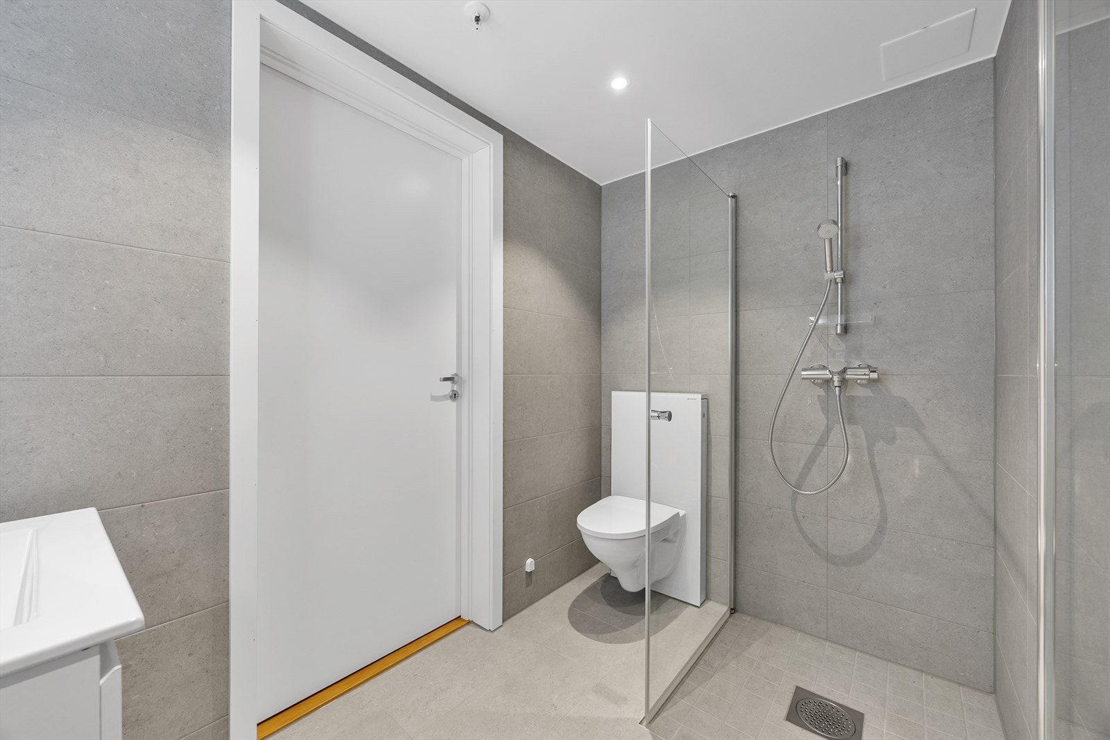 Badet er flislagt med store, moderne fliser og utstyrt med vegghengt toalett. Galleribilde