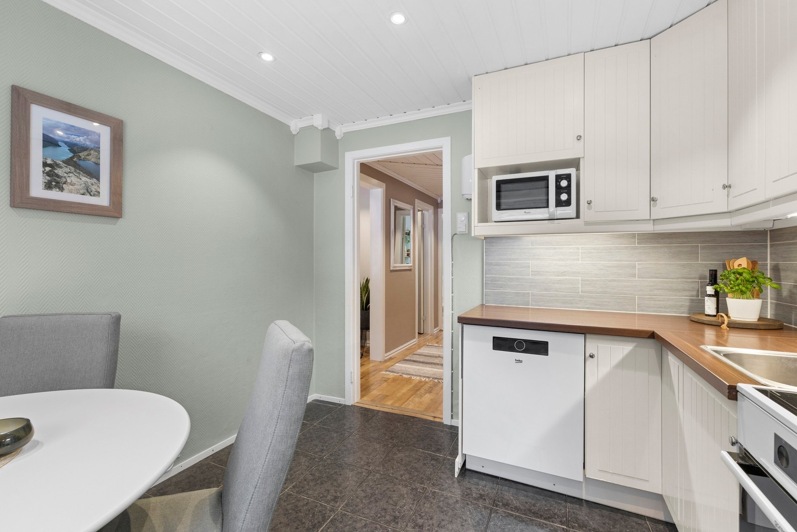 Hvitt IKEA kjøkken med god skapplass og rikelig med benkeplass. Nye fliser over benk og benkeplate fra 2014 gir et moderne uttrykk Galleribilde