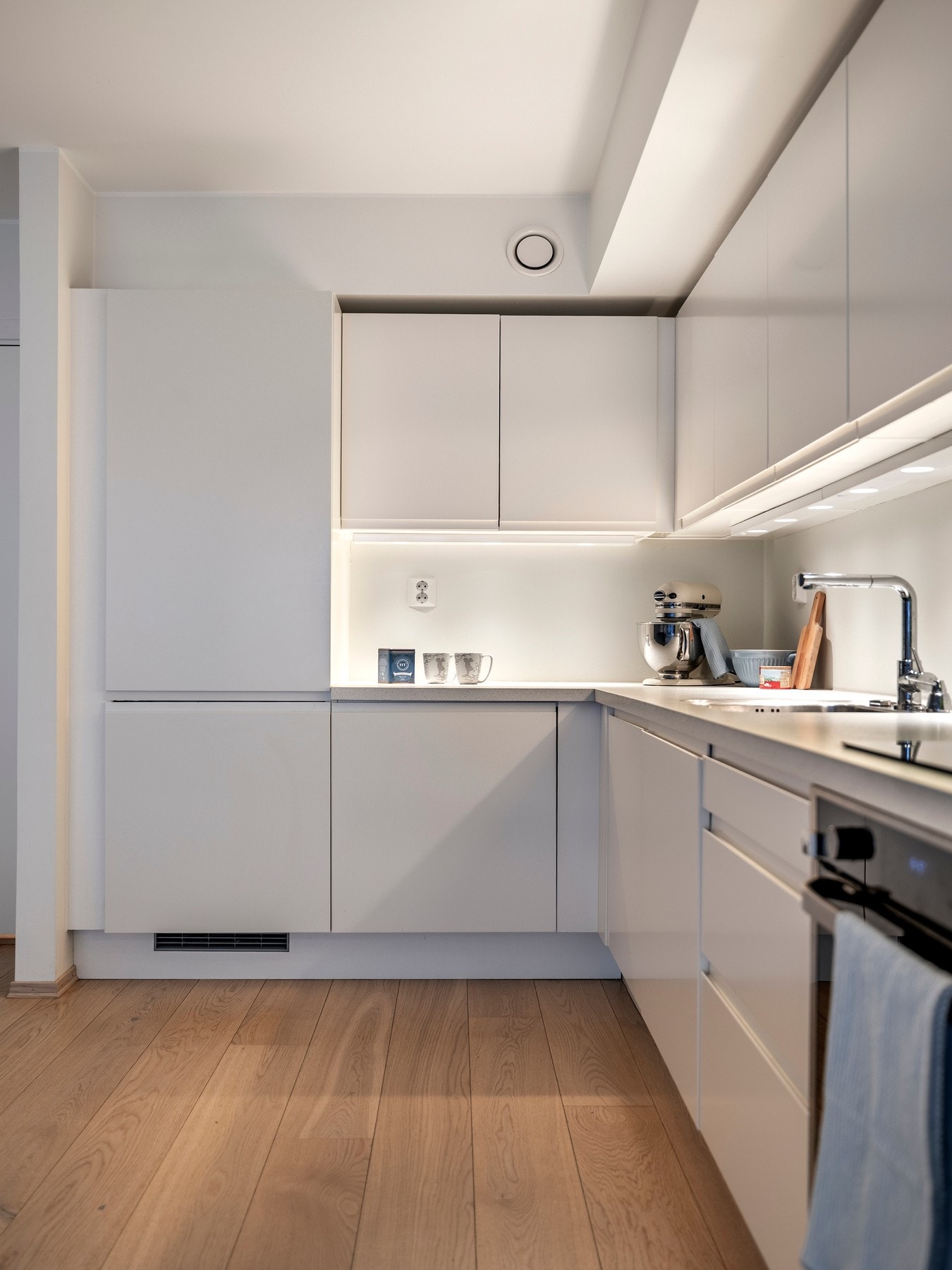 Moderne kjøkkeninnredning med lyse, glatte fronter og laminerte benkeplater med underlimt kum. Galleribilde