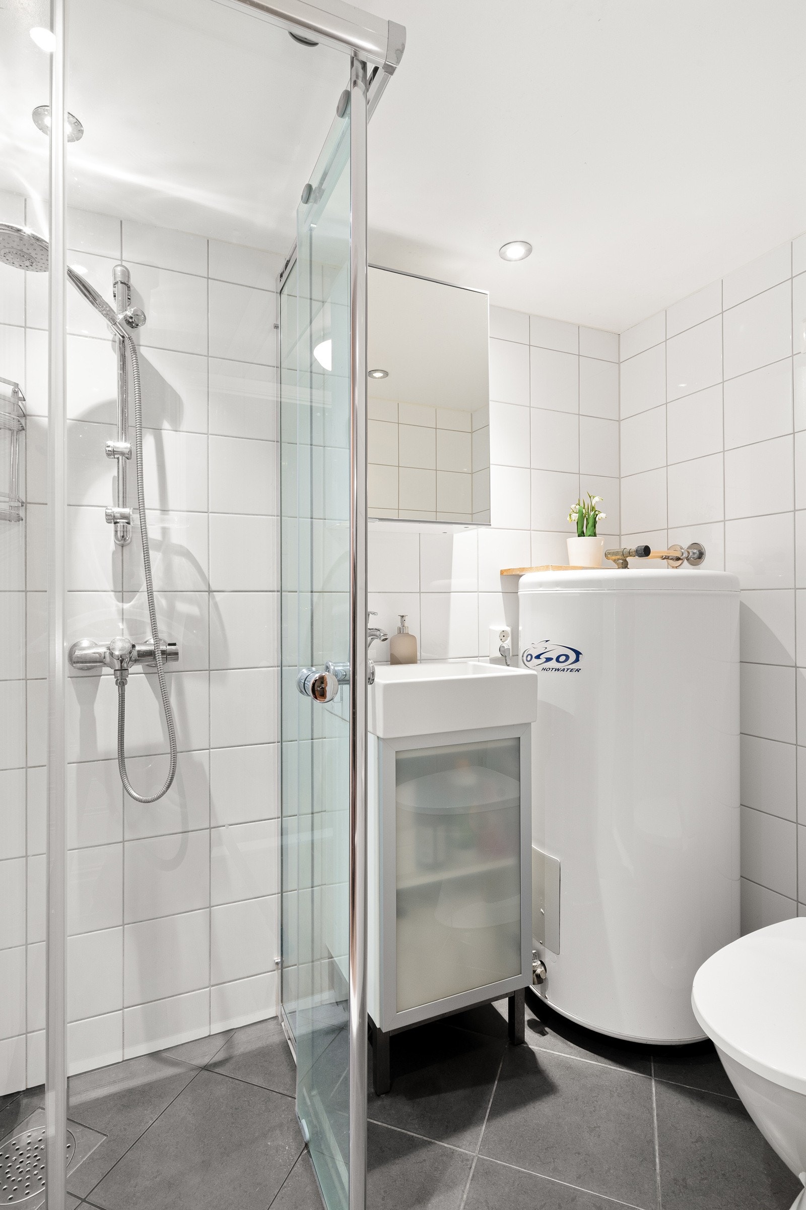 Badet i kjelleretasjen er også renovert av forrige eier og fremstår som lyst og praktisk med hvite fliser på veggene og mørke fliser på gulvet, kombinert med behagelig gulvvarme. Galleribilde