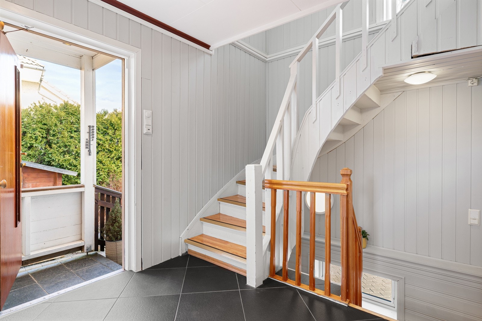 Innenfor døren møtes du av en lys og romslig entré med mørke fliser på gulvet. Det er god plass til garderobeløsning. Her finner du også trappen som leder videre opp til 2. etasje og ned til kjelleren. Galleribilde