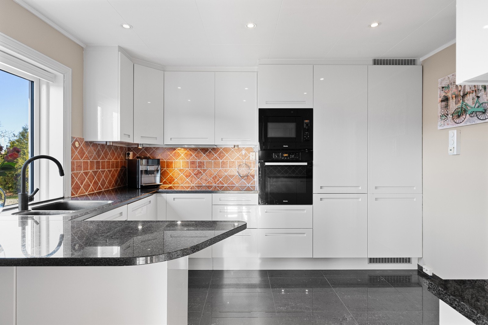 Kjøkkenet fremstår som pent og velholdt, med rikelig skap- og benkeplass som gir gode arbeidsforhold i hverdagen Galleribilde