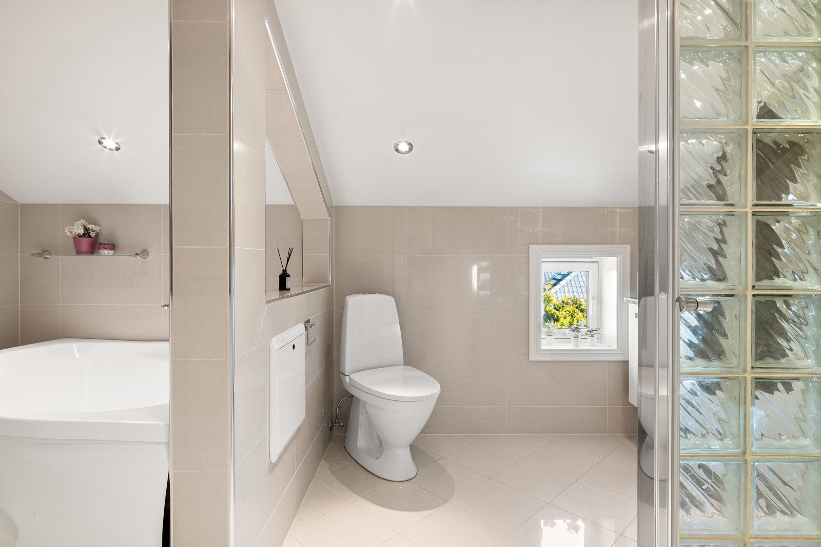 Den ene sonen er innredet med heldekkende servant montert på skap-/skuffeseksjon, speil, dusjhjørne og frittstående toalett Galleribilde