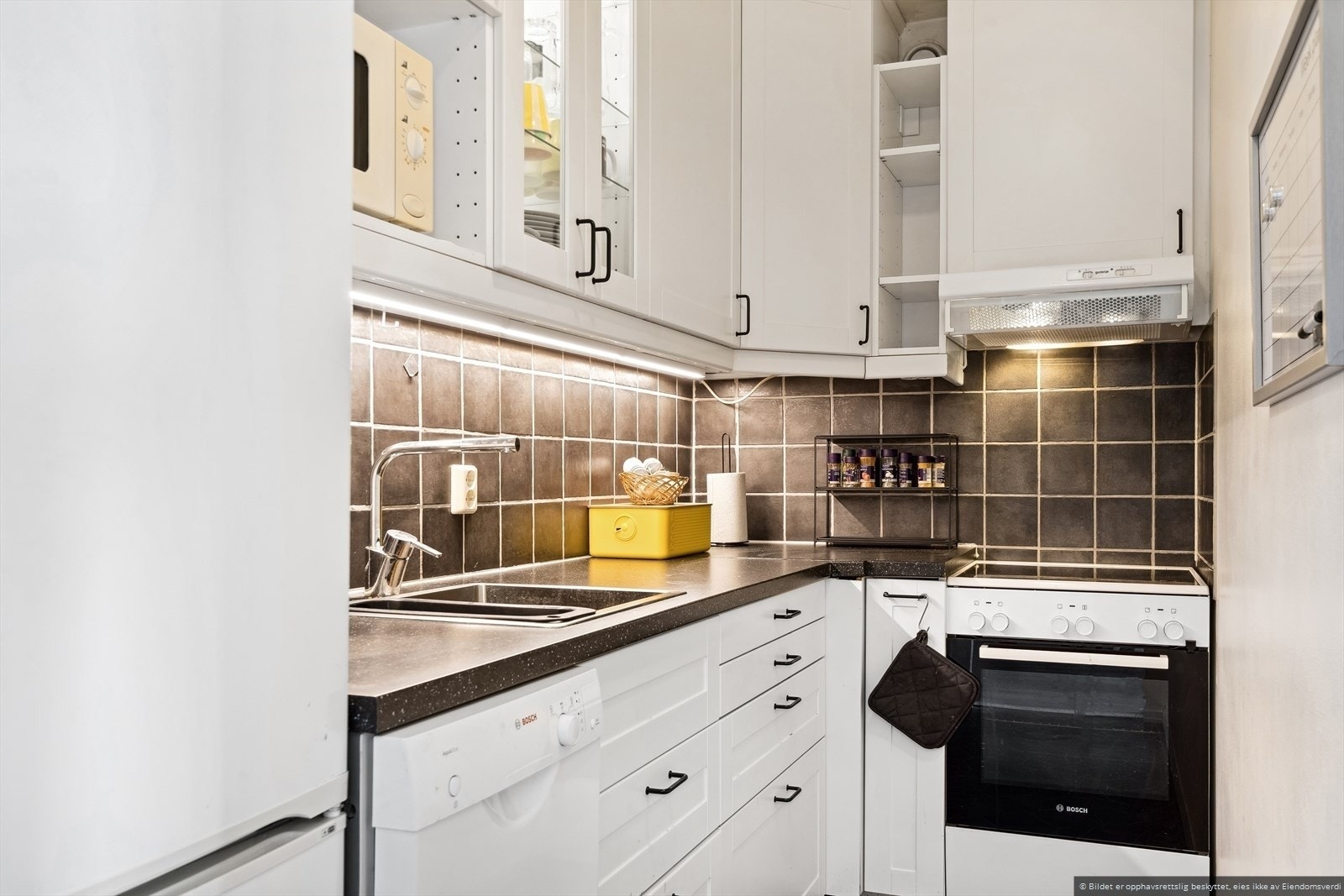 Boligen har et stilfullt kjøkken med hvite fronter og frittstående hvitevarer. Galleribilde