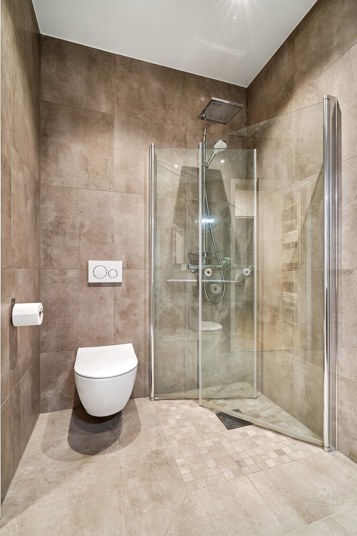 Badet er utstyrt med vegghengt toalett, dusjhjørne med rainshower og innfellbare glassdører. Galleribilde