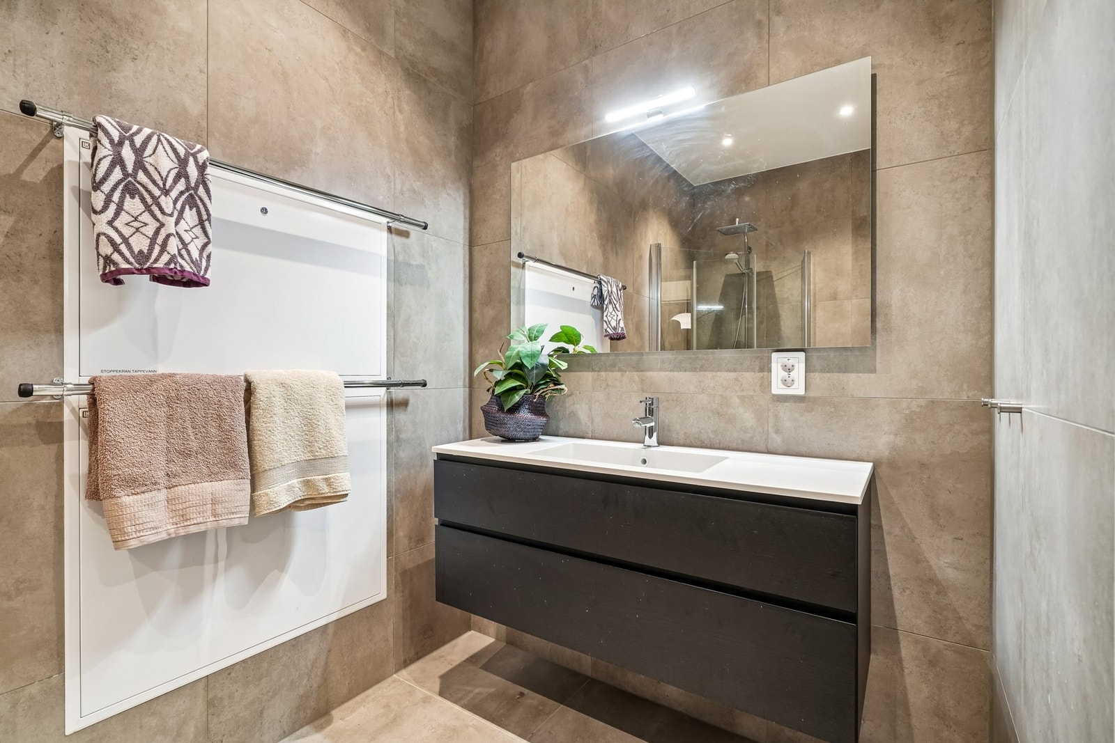 Badet er pent helfliset med 60x60 fliser og det er vannbåren varme i gulvet. Areal på 5,3 kvm. Galleribilde