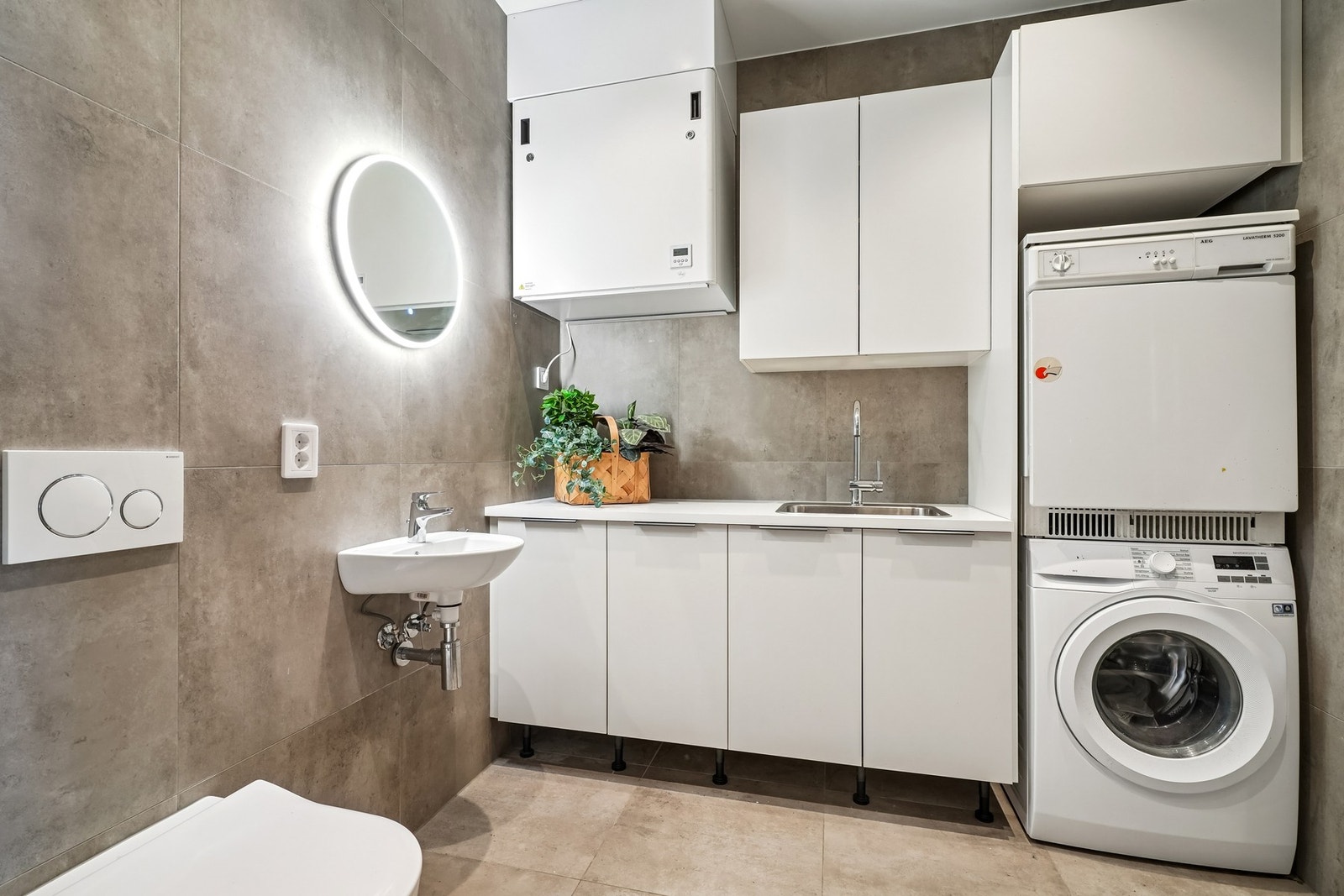 Bad/vaskerom helfliset med 60x60 fliser. Vannbåren varme i gulvet. Praktisk innredning med god oppbevaring og benkeplate med vask. Areal: ca. 5,4 kvm. Galleribilde