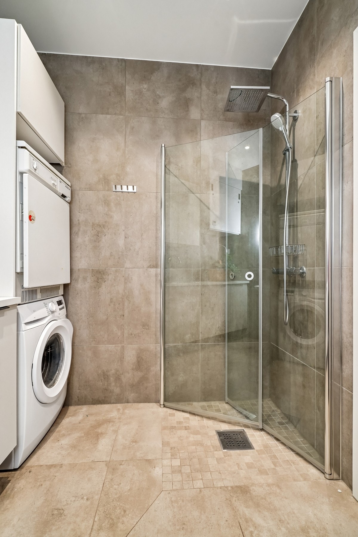 Opplegg for vaskemaskin og tørketrommel. Utstyrt med vegghengt servant, vegghengt wc og dusjhjørne med rainshower og innfellbare dusjdører i glass. Galleribilde