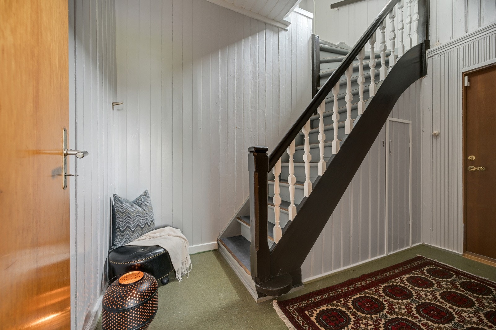 Velkommen inn i entrèen med lyse vegger og trapp opp til boligens andre etasje Galleribilde