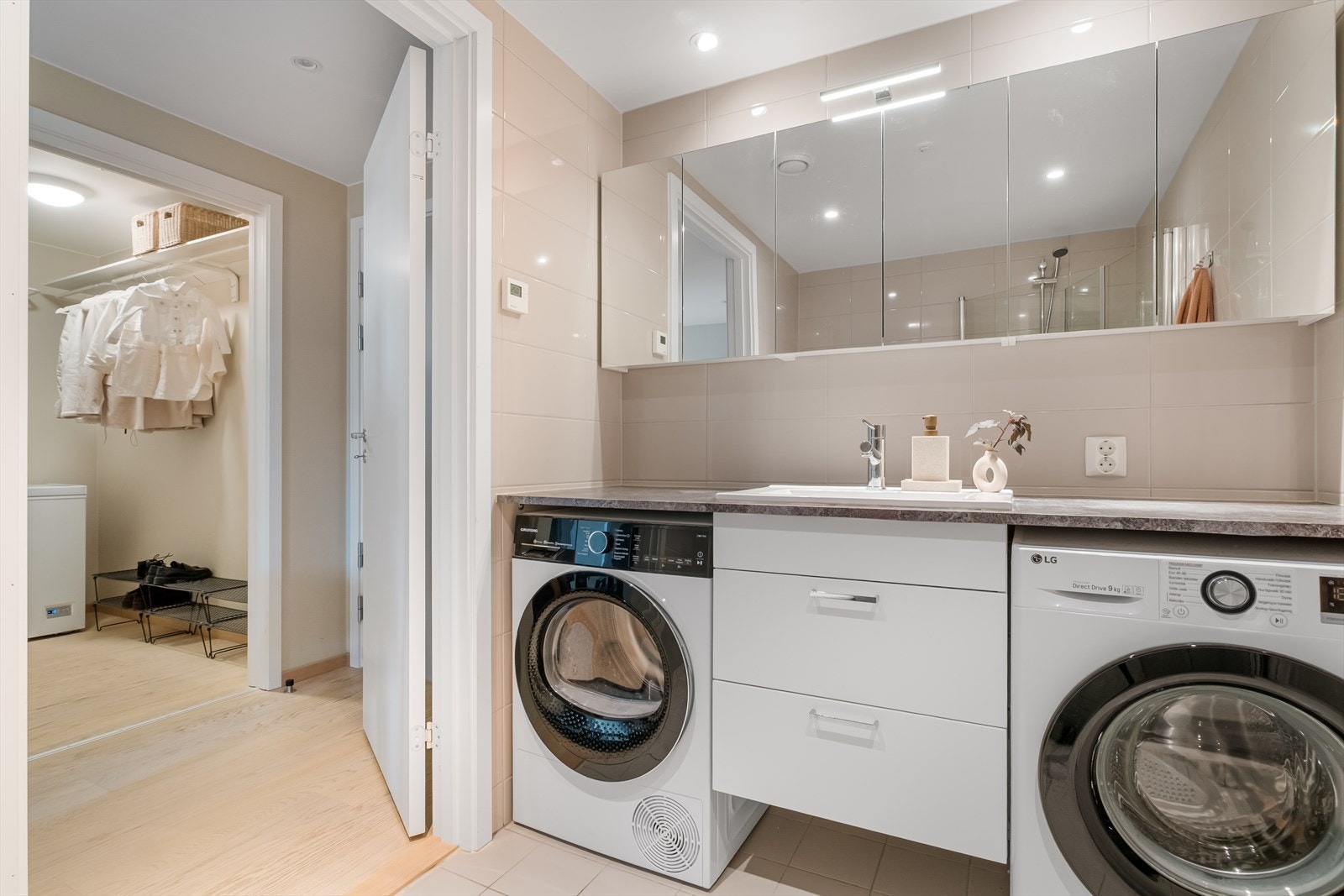 En praktisk løsning med vaskemaskin og tørketrommel under benk. Rikelig med skapplass i speilskapene langs hele den ene veggen. Galleribilde