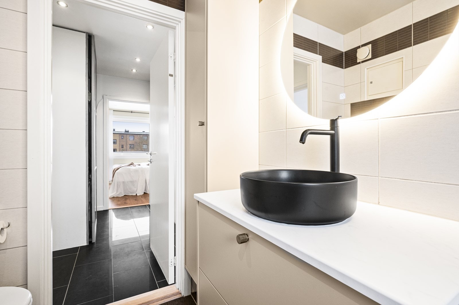 Stilren servant med ettgrepsbatteri og et stort speil med integrert belysning. Galleribilde