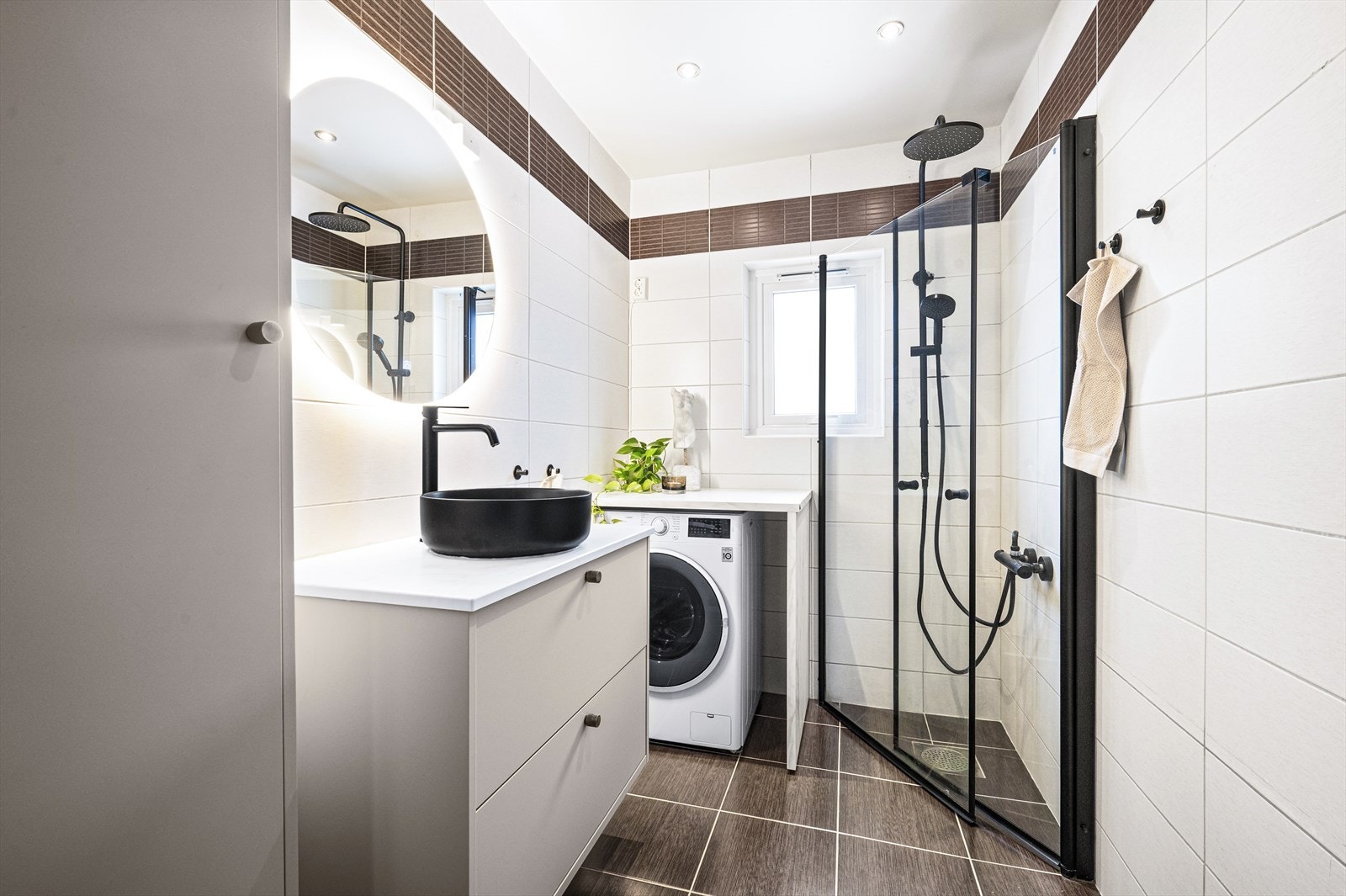 Badet har moderne innredning, vegghengt toalett og opplegg for vaskemaskin. Innredningen ble byttet i 2025. Galleribilde