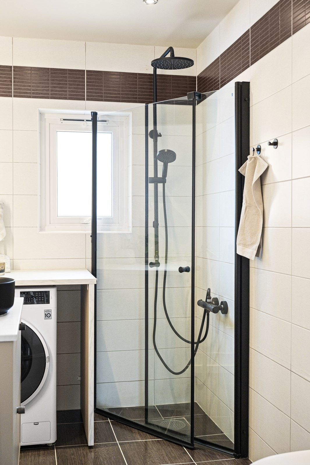 Dusjhjørne med innfellbare dører i glass og sorte profiler som ble byttet i 2025. Galleribilde