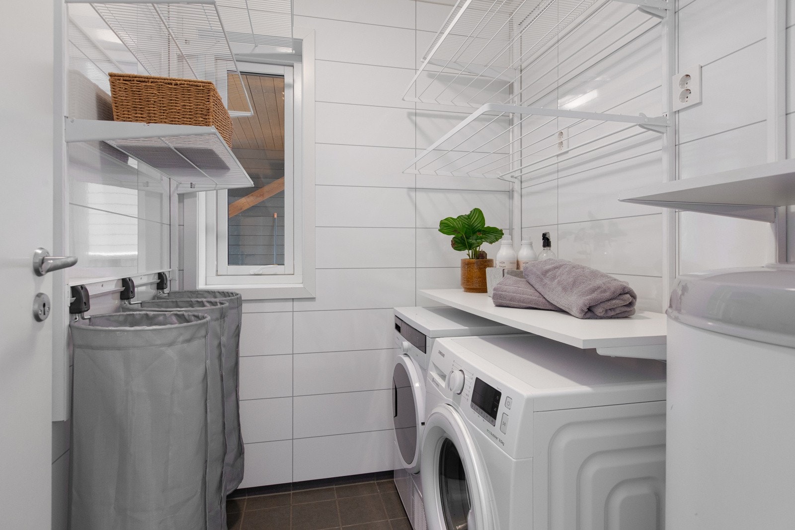 Videre inn i etasjen finner du et praktisk, separat vaskerom, innredet med hyller, oppheng og benk som gir gode arbeids- og oppbevaringsmuligheter. Det er også opplegg for både vaskemaskin og tørketrommel. Galleribilde