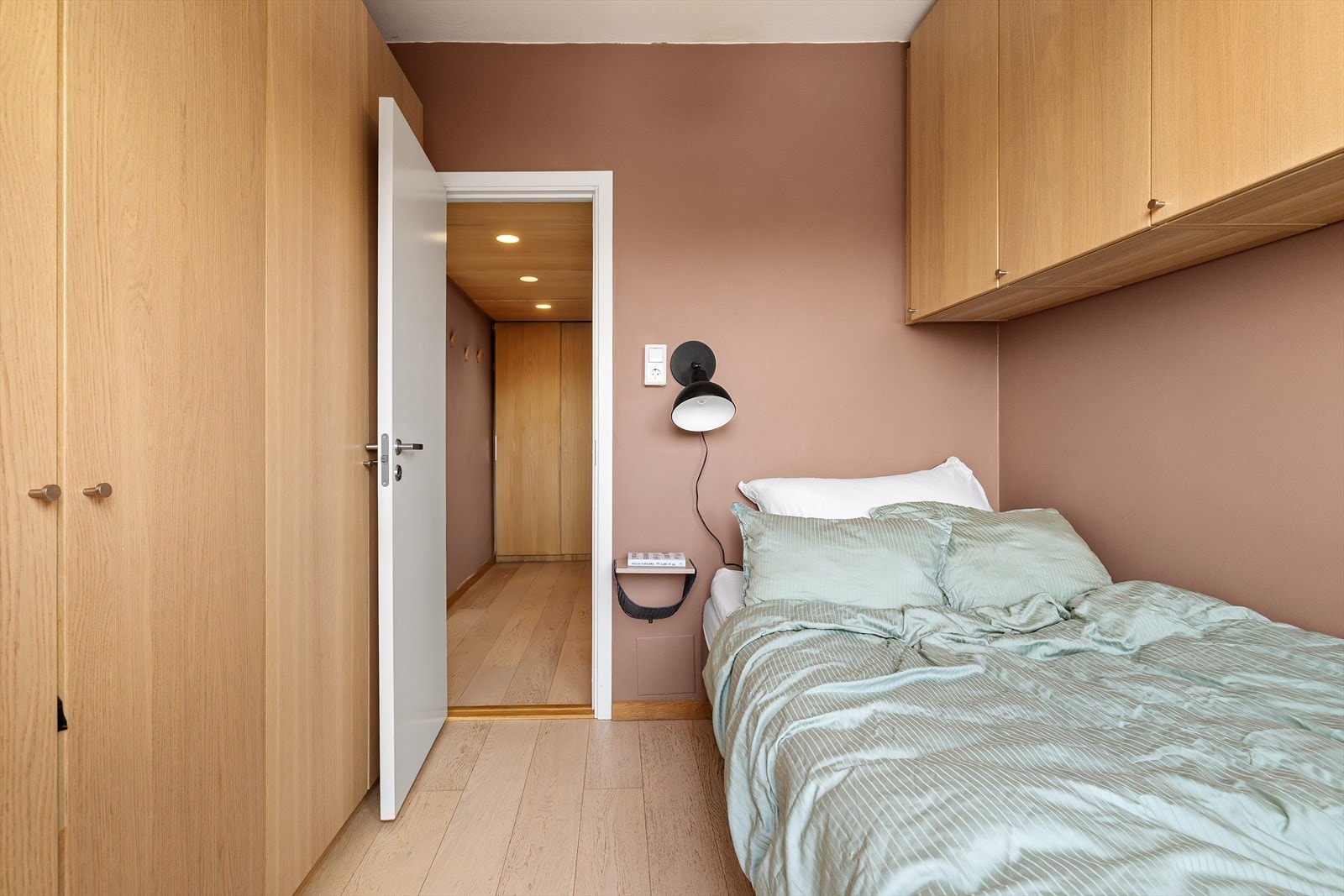 Overskapene gir rikelig med plass til klær og øvrig oppbevaring, samtidig som løsningen fremstår både plassbesparende og visuelt helhetlig. Galleribilde