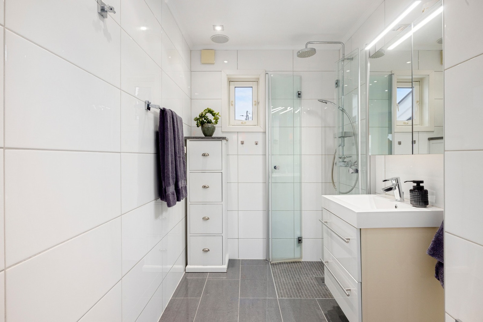 Pent flislagt bad med gulvvarme. Innredningen består av servantskap, dusjhjørne, toalett og speilskap. Galleribilde