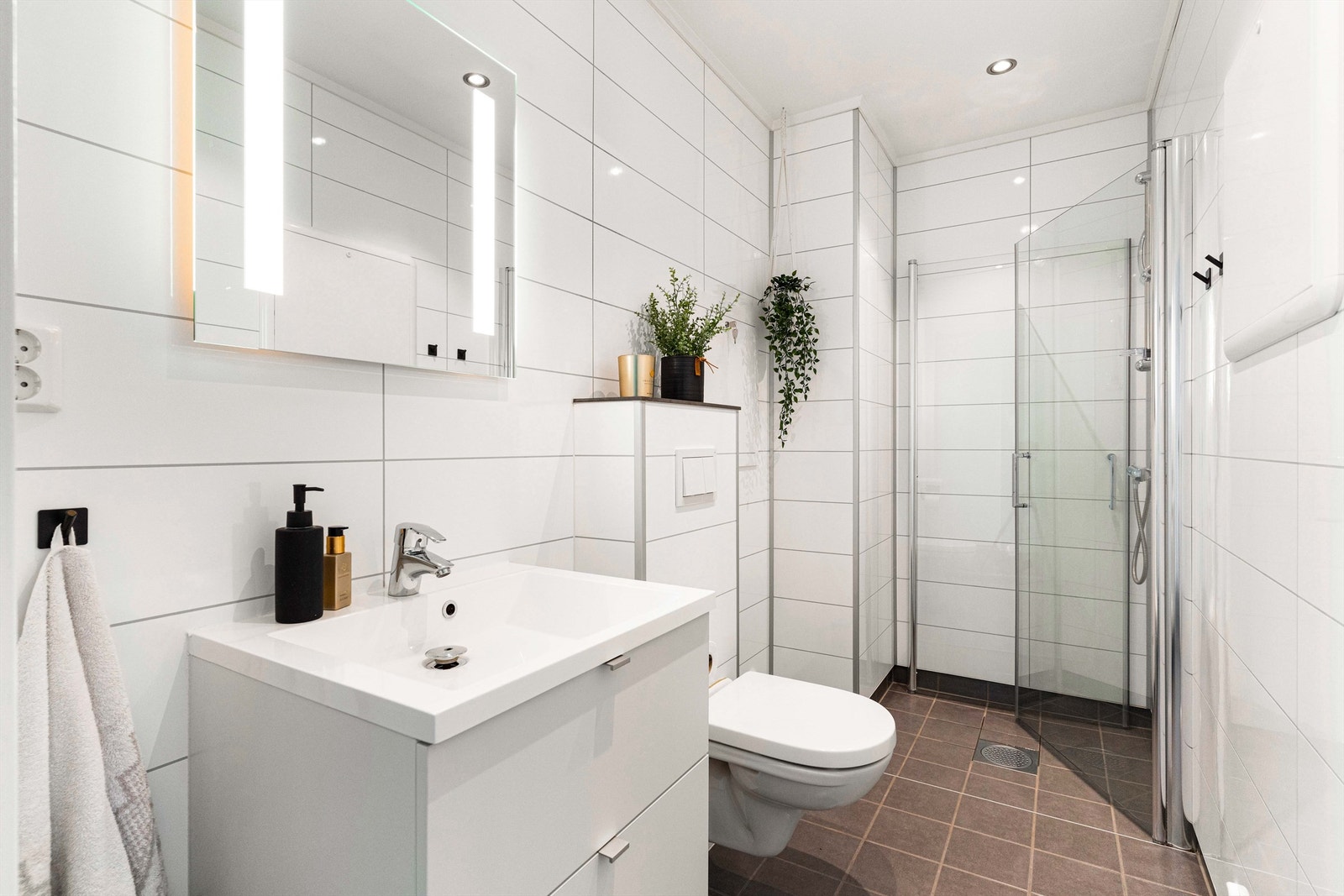 Badet fra byggeår er utstyrt med elektriske varmekabler. Det inneholder et vegghengt toalett, dusjhjørne og et vegghengt servantskap med heldekkende servant. Galleribilde