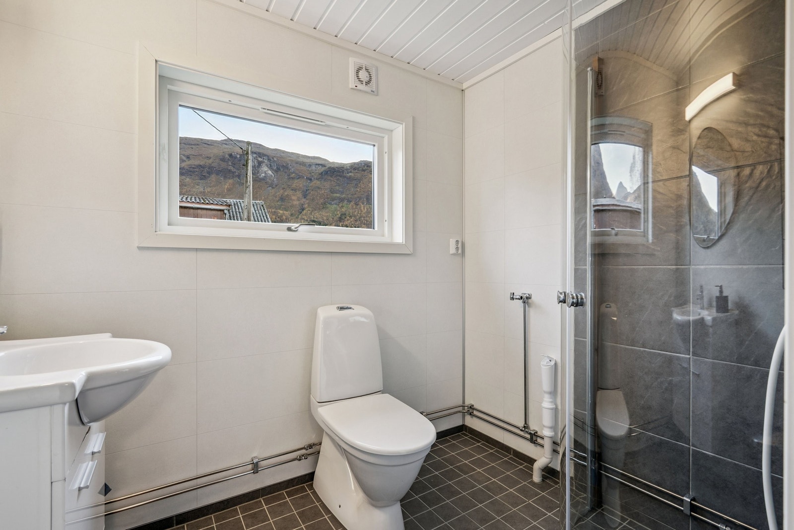 Nyoppusset bad med toalett og dusj. Plass til å sette inn toppmatet vaskemaskin. Her også fjellutsikt til tannpussen. Galleribilde