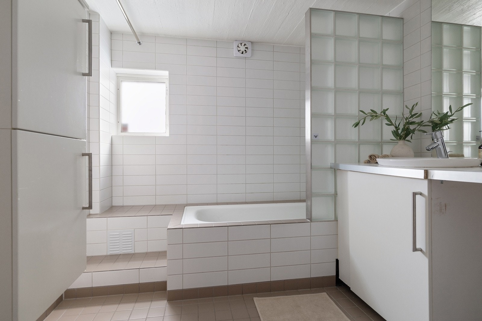 Rommet har flislagt gulv med elektriske varmekabler, flislagte vegger og malt mur i tak/himling, noe som gir en robust og praktisk løsning for kombinert bad- og vaskeromsfunksjon. Galleribilde