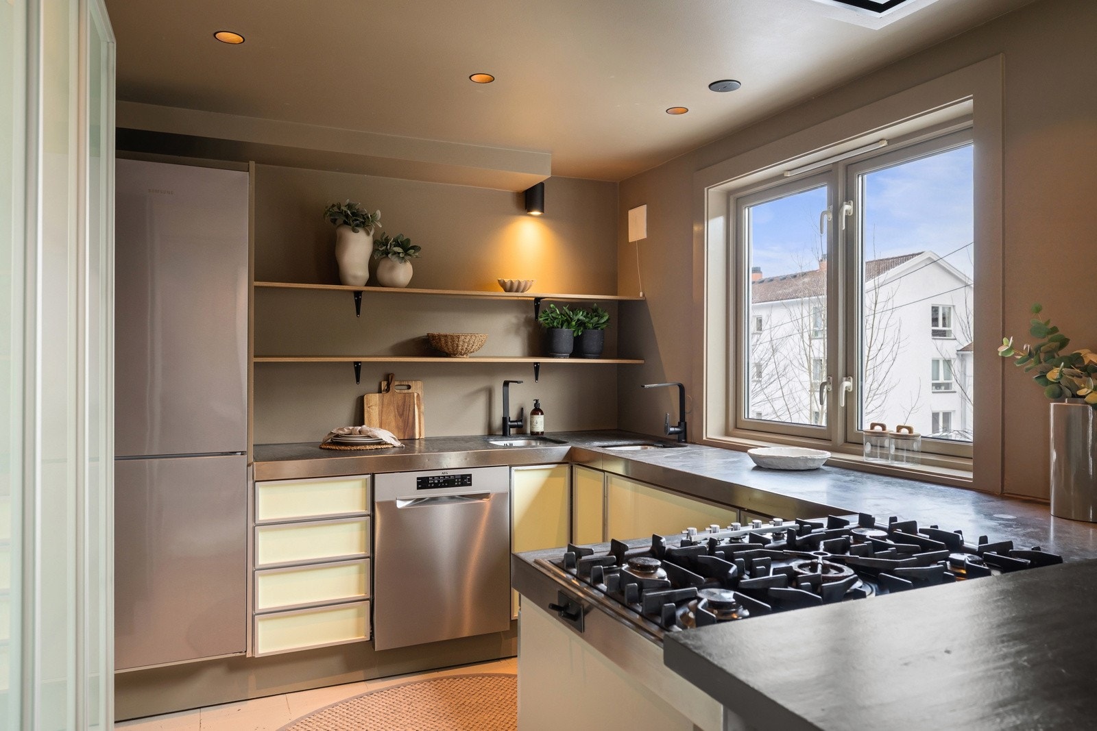 Åpne hyller og moderne detaljer gir et luftig uttrykk, mens gasskoketoppen og de integrerte hvitevarene gjør kjøkkenet funksjonelt i hverdagen. Galleribilde