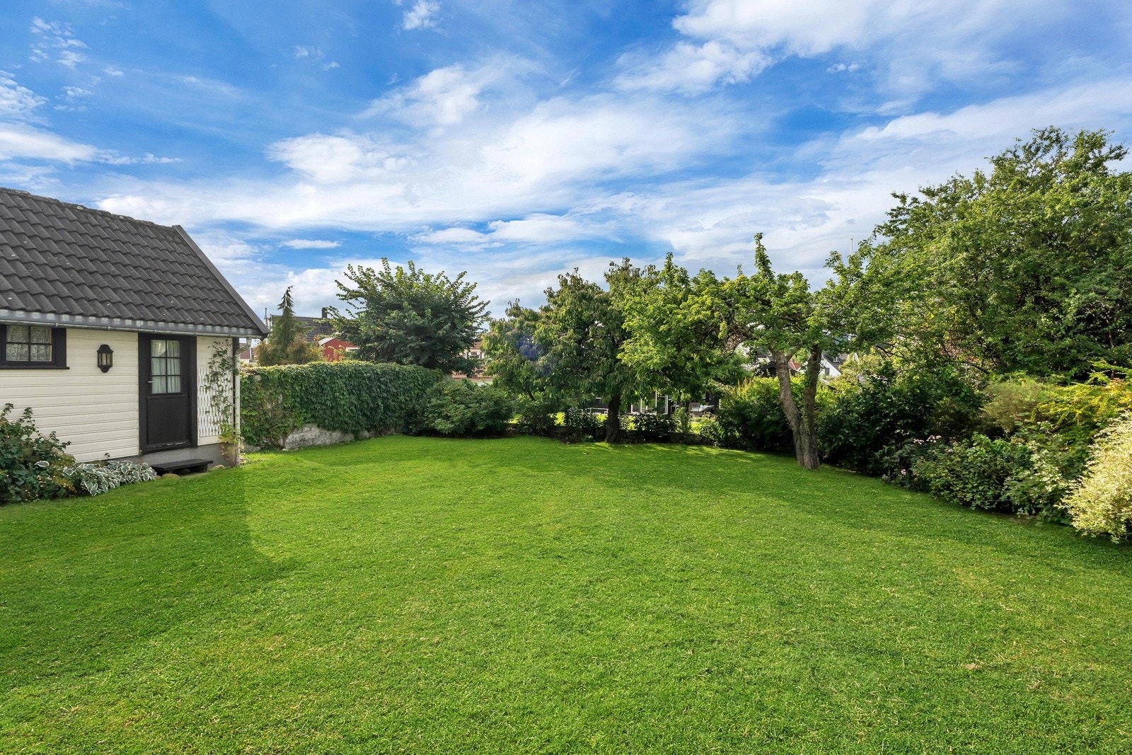 Den solrike hagen er særdeles pent opparbeidet med plen, blomsterbed samt eple- og kirsebærtre. Galleribilde