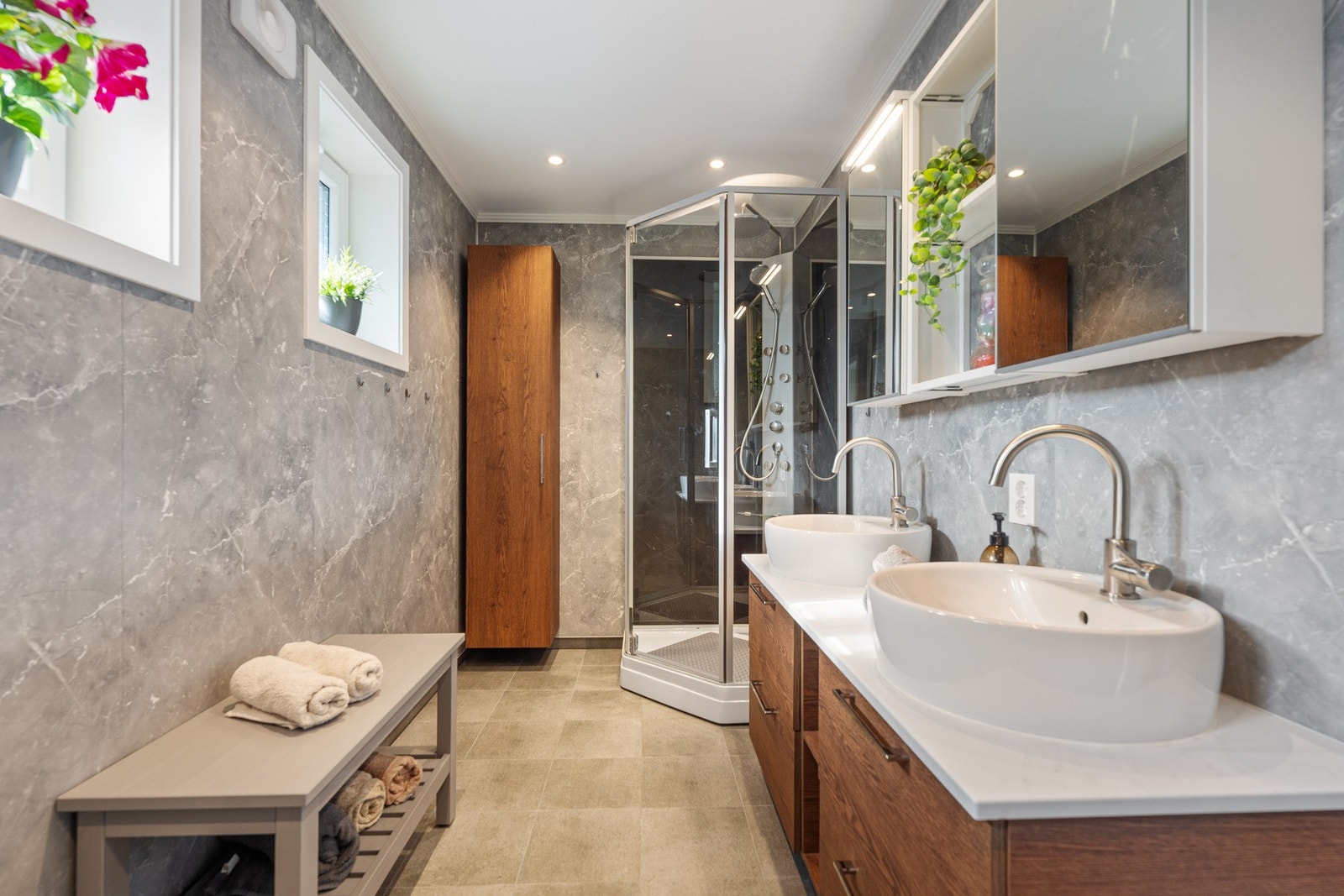 Badet har vegghengt toalett, innredning med to servanter samt dusjkabinett. Galleribilde