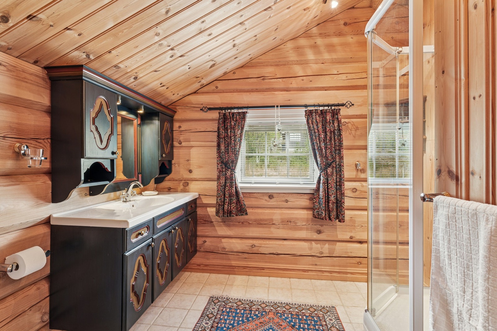 2. etasje har et romslig bad, utstyrt med både dusjkabinett og gulvstående vannklosett. Innredningen består av servant, unikt servantskap med flotte detaljer, speil og godt med lagringsplass. Badet har i likhet med soverommet mønet himling. Galleribilde