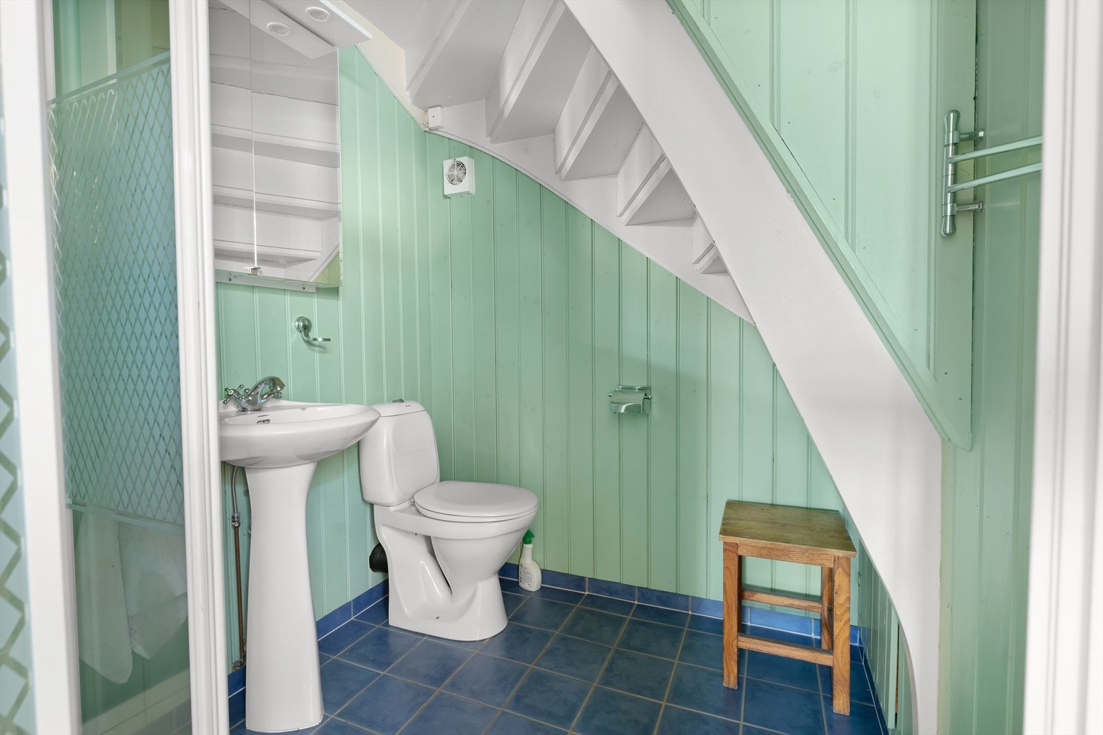 Blå fliser og grønnmalte panelvegger gir badet et praktisk og lettstelt uttrykk. Galleribilde