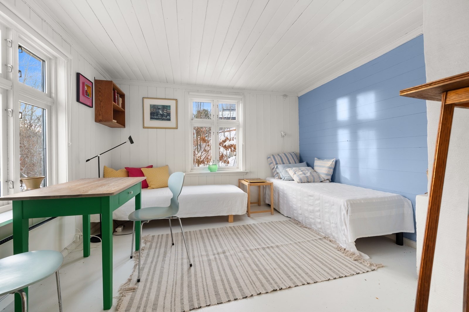 Flere vinduer gir godt med naturlig lys i rommet med blå aksentvegg. Galleribilde