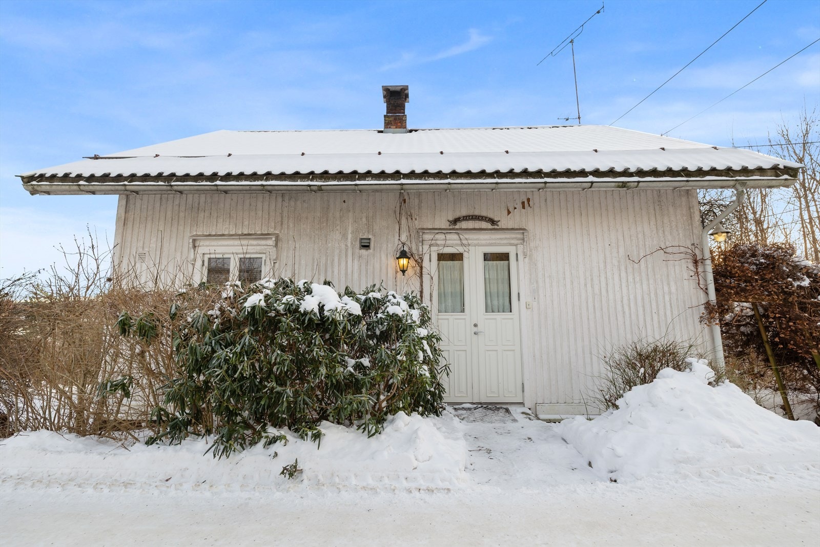 Inngangspartiet er omkranset av vintergrønne busker som gir liv til fasaden. Galleribilde
