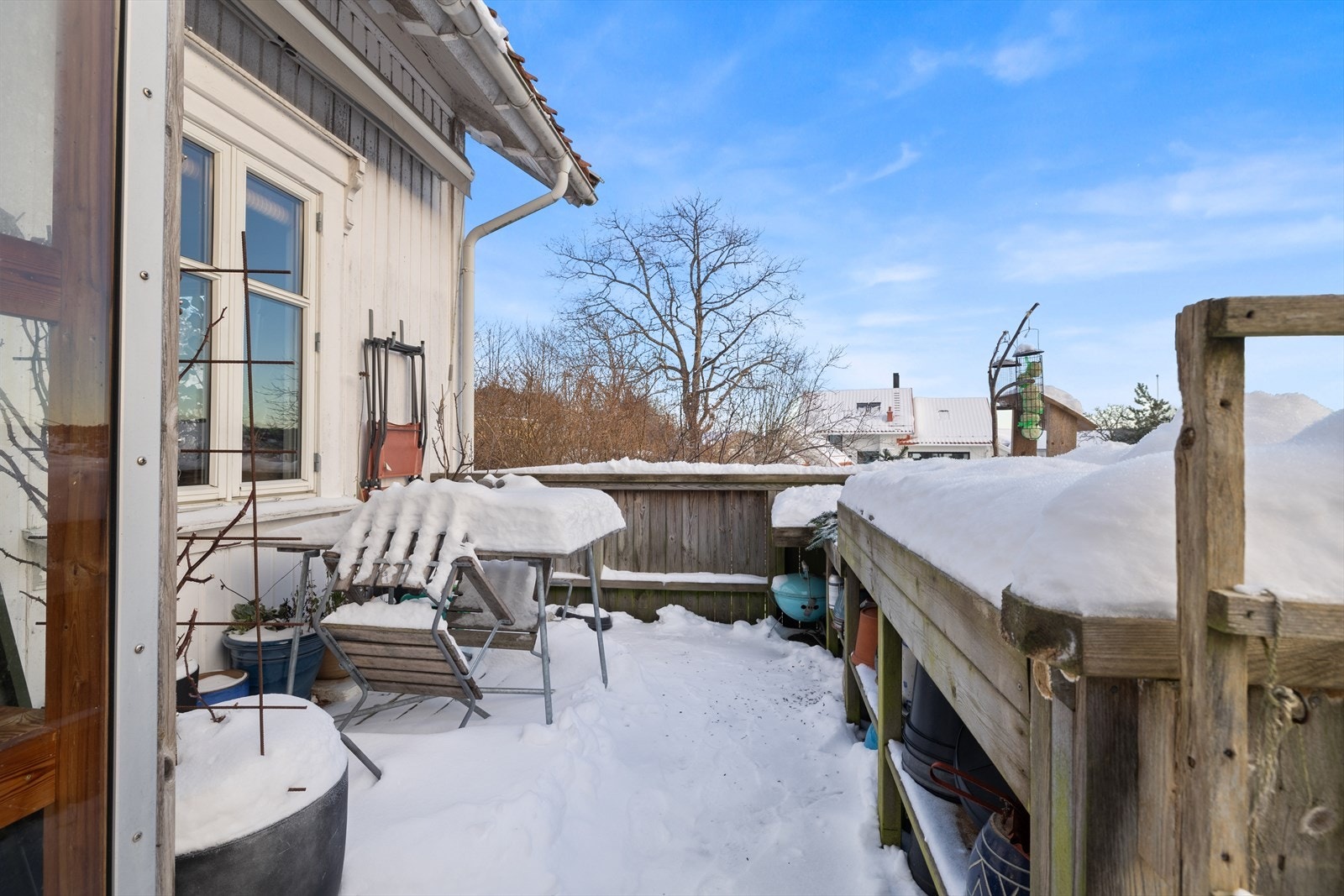 Terrassen er snødekt og har utsikt mot et rolig nabolag med trær i bakgrunnen. Galleribilde