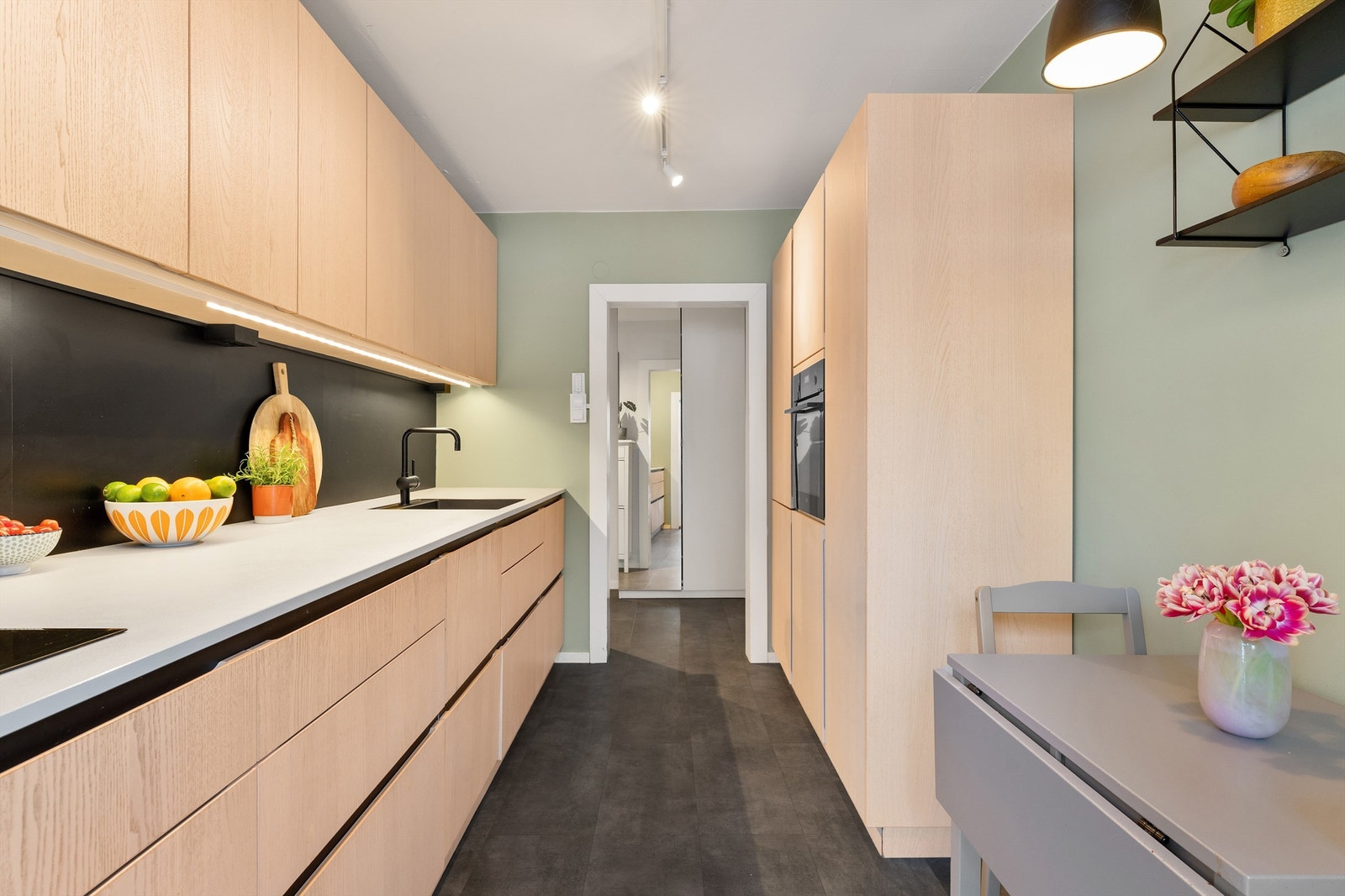 Kjøkkenet er praktisk utformet med mye lagringsplass og rom for et frokostbord Galleribilde