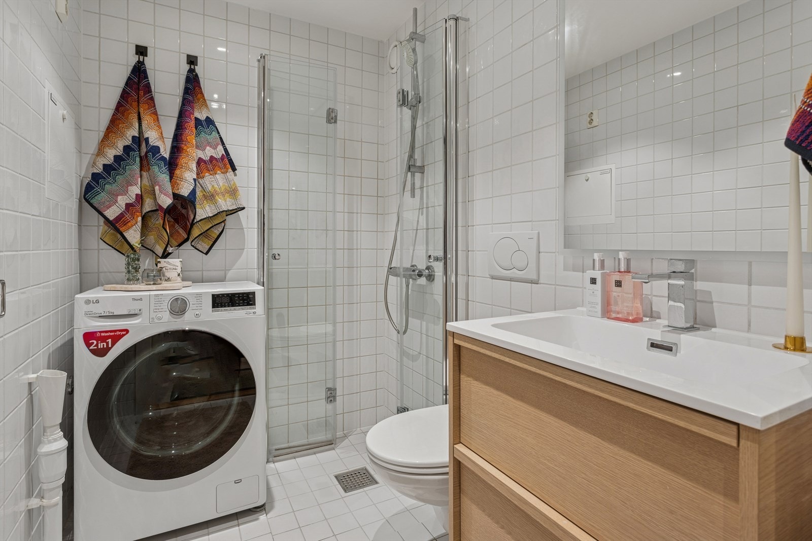 Moderne og helfliset bad med dusjløsning, vegghengt toalett og opplegg for vaskemaskin. Galleribilde