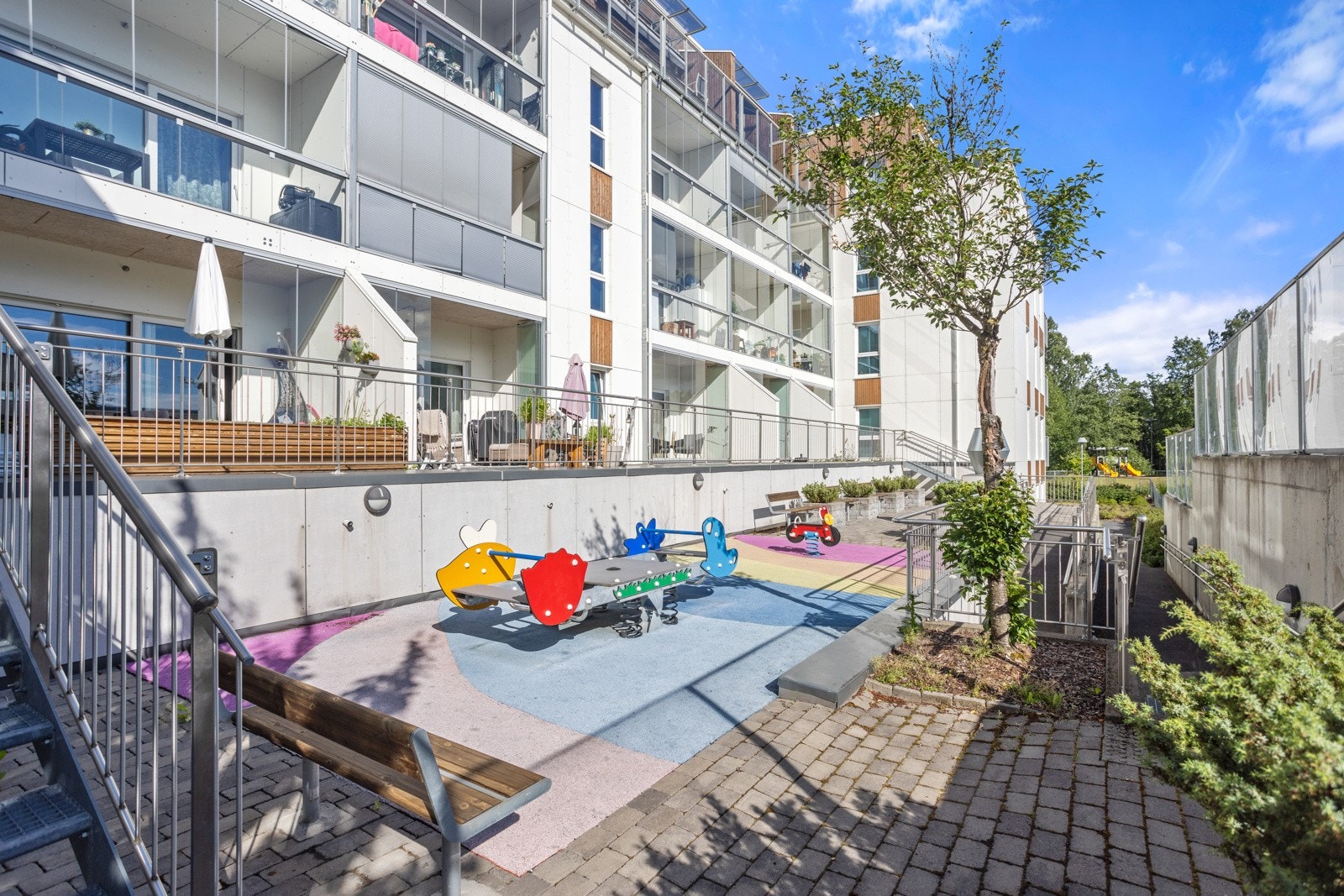 Fellestomten er pent opparbeidet med steinbelagte områder, frodige prydbusker og stemningsfull utebelysning, og det er lekestativer og sittebenker til felles anvendelse i bakgården Galleribilde