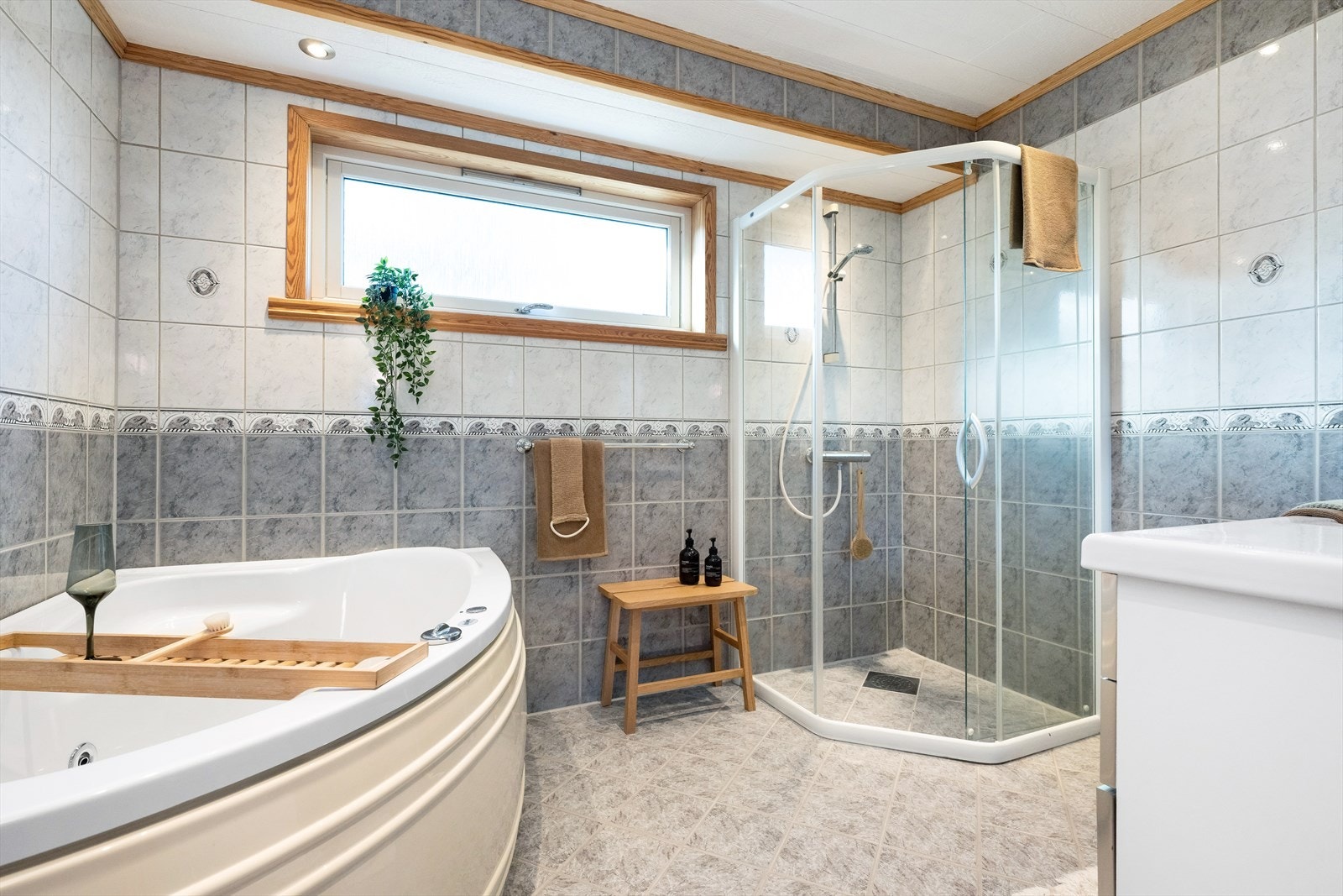 Hovedbadet i boligen er helfliset og pent, med innredning som dusjhjørne, badekar og servantinnredning med skap og skuffer. Galleribilde