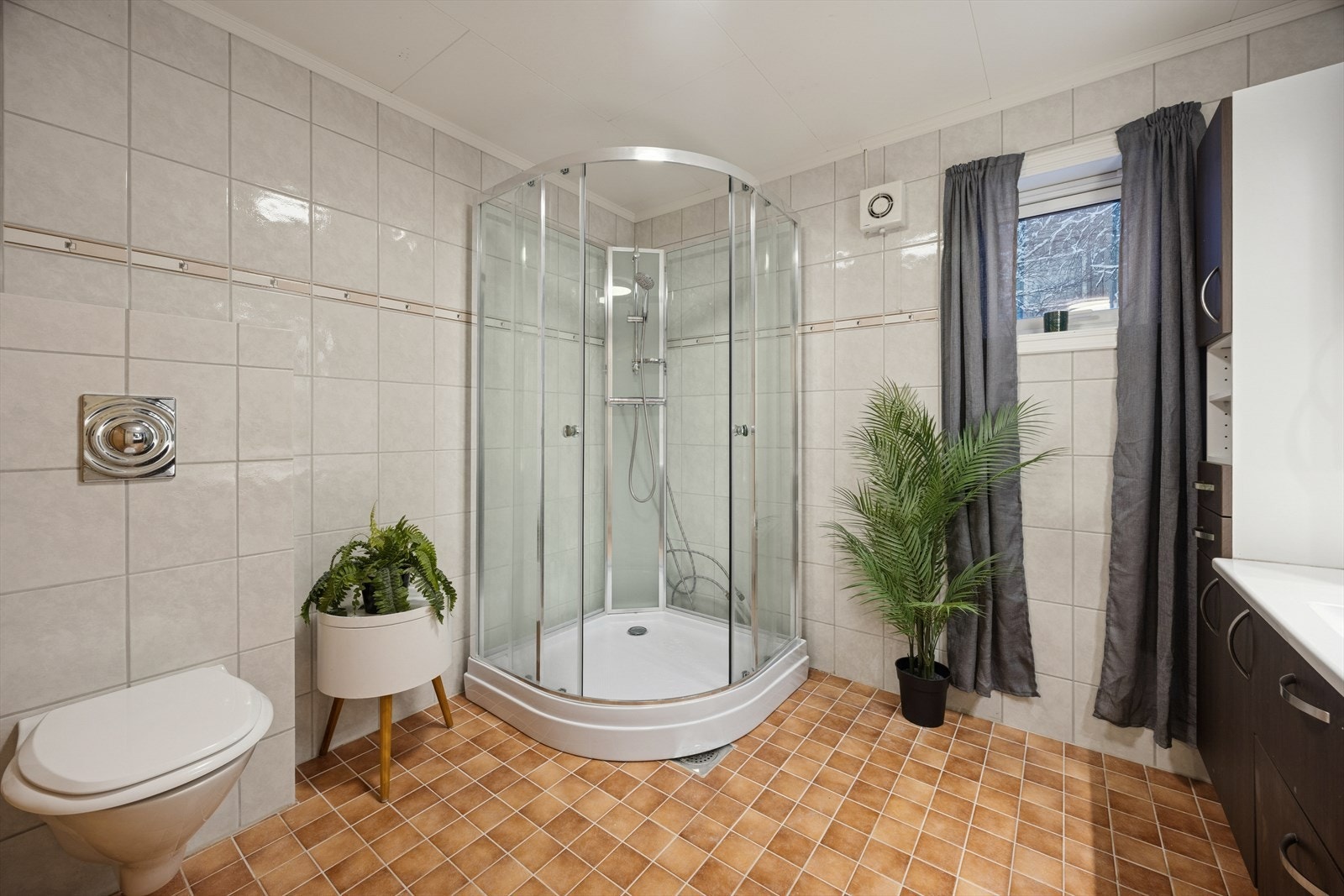 Badet er innredet med dusjkabinett, vegghengt toalett og servant. Galleribilde