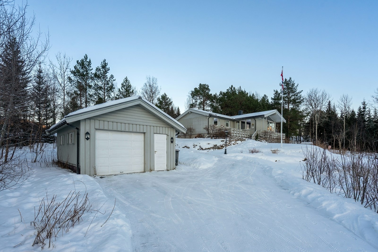 Garasjen er innredet med en liten arbeidsbenk med verktøyhylle og skap. Galleribilde
