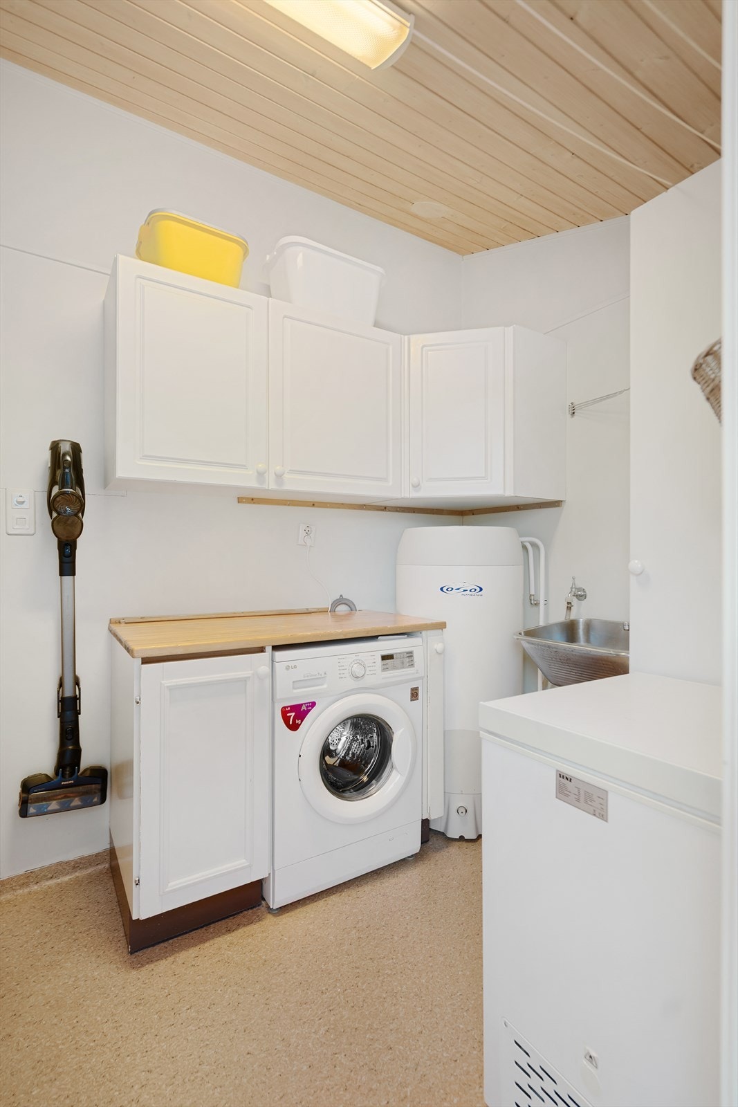 Vaskerom har utslagsvask, overskap, benkeplate i heltre med skap og opplegg for vaskemaskin under og ett høyskap. Galleribilde