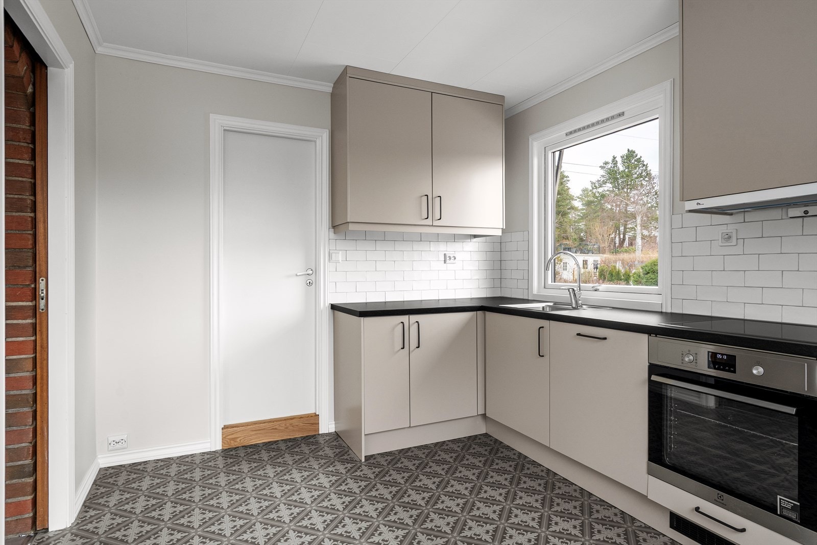 Effektivt u-kjøkken med integrerte hvitevarer, kjøkkenventilator med avtrekk ut og klassisk flislagt benkerygg. Fra kjøkkenet er det inngang til vaskerom. Galleribilde